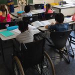 Disable schoolboy studying at desk in classroom